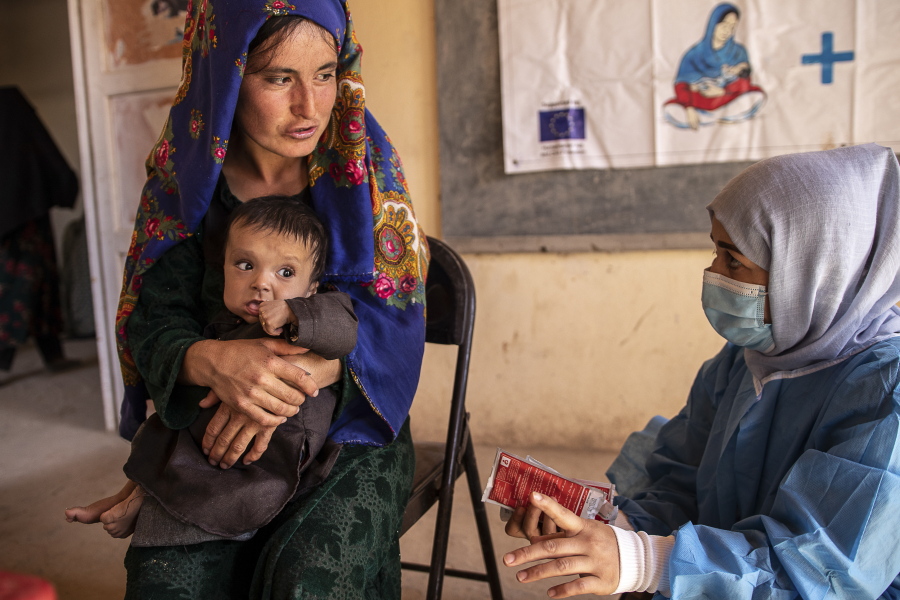 A Save the Children nutrition counsellor, right, explains to Nelab, 22, how to feed her 11-month-old daughter, Parsto, with therapeutic food, which is used to treat severe acute malnutrition, in Sar-e-Pul province of Afghanistan, Thursday, Sept. 29, 2022. A senior U.N. official in Afghanistan met the deputy prime minister of the Taliban-led government to discuss a ban on women working for non-governmental groups. Save the Children is one of the major aid agencies that suspended its operations in Afghanistan after the ban was announced.