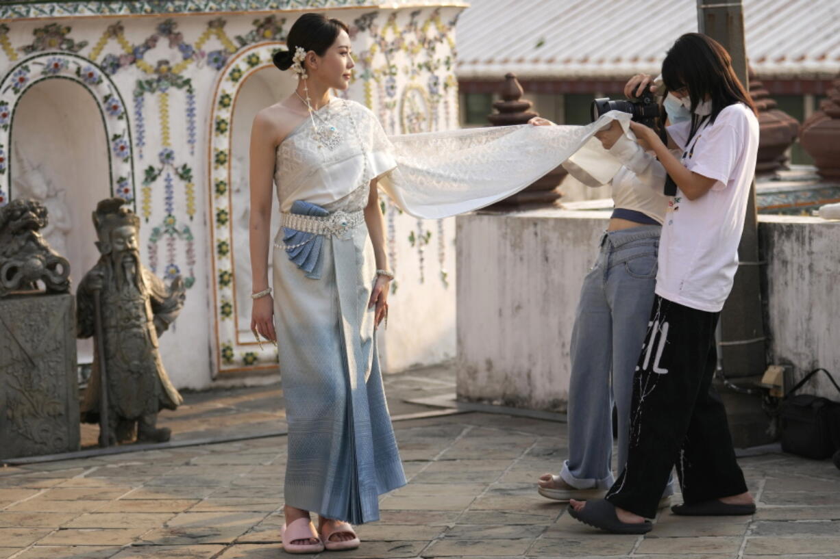 A Chinese tourist in traditional Thai costume poses for a photograph at Wat Arun or the "Temple of Dawn" in Bangkok, Thailand on Jan. 12, 2023. A hoped-for boom in Chinese tourism in Asia over next week's Lunar New Year holidays looks set to be more of a blip as most travelers opt to stay inside China if they go anywhere.