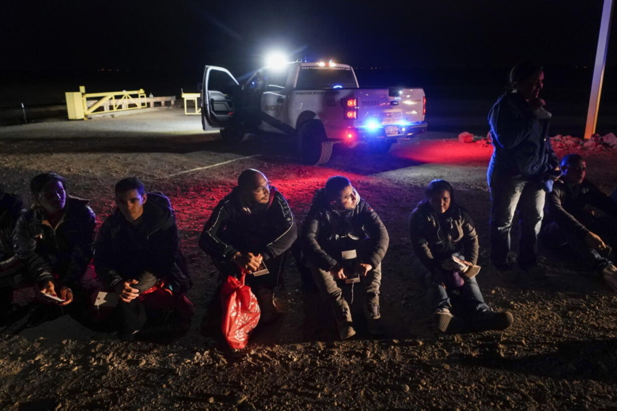 FILE - Migrants wait to be processed after crossing the border on Jan. 6, 2023, near Yuma, Arizona. U.S. authorities have seen a 97% decline in illegal border crossings by migrants from Cuba, Haiti, Nicaragua and Venezuela since Mexico began accepting those expelled under a pandemic-era order, the Biden administration said Wednesday, Jan. 25, 2023.