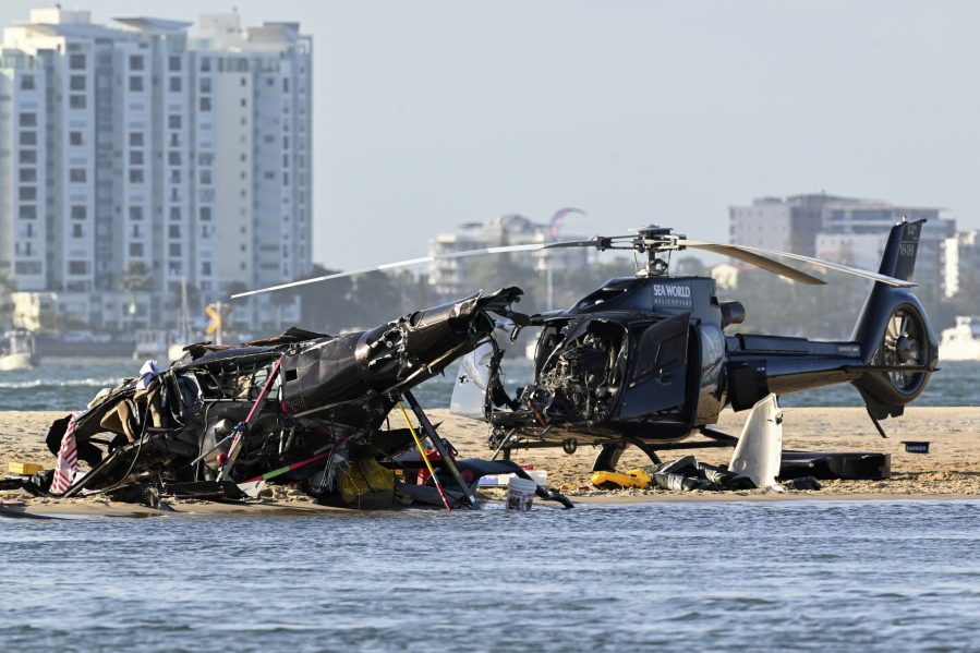 Two cashed helicopters sit on the sand at a collision scene near Seaworld, on the Gold Coast, Australia, Monday, Jan. 2, 2023. The 2 helicopters collided killing several passengers and critically injuring a few others in a crash that drew emergency aid from beachgoers enjoying the water during the southern summer.