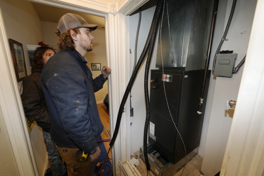 John Paul, front, and David Valenzuela work to install a heat pump in an 80-year-old rowhouse Friday, Jan. 20, 2023, in northwest Denver.