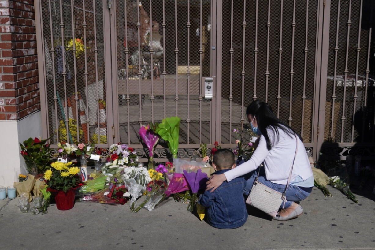 A woman comforts her son while visiting a makeshift memorial outside Star Ballroom Dance Studio in Monterey Park, Calif., Monday, Jan. 23, 2023. Authorities searched for a motive for the gunman who killed multiple people at the ballroom dance studio during Lunar New Year celebrations. (AP Photo/Jae C.