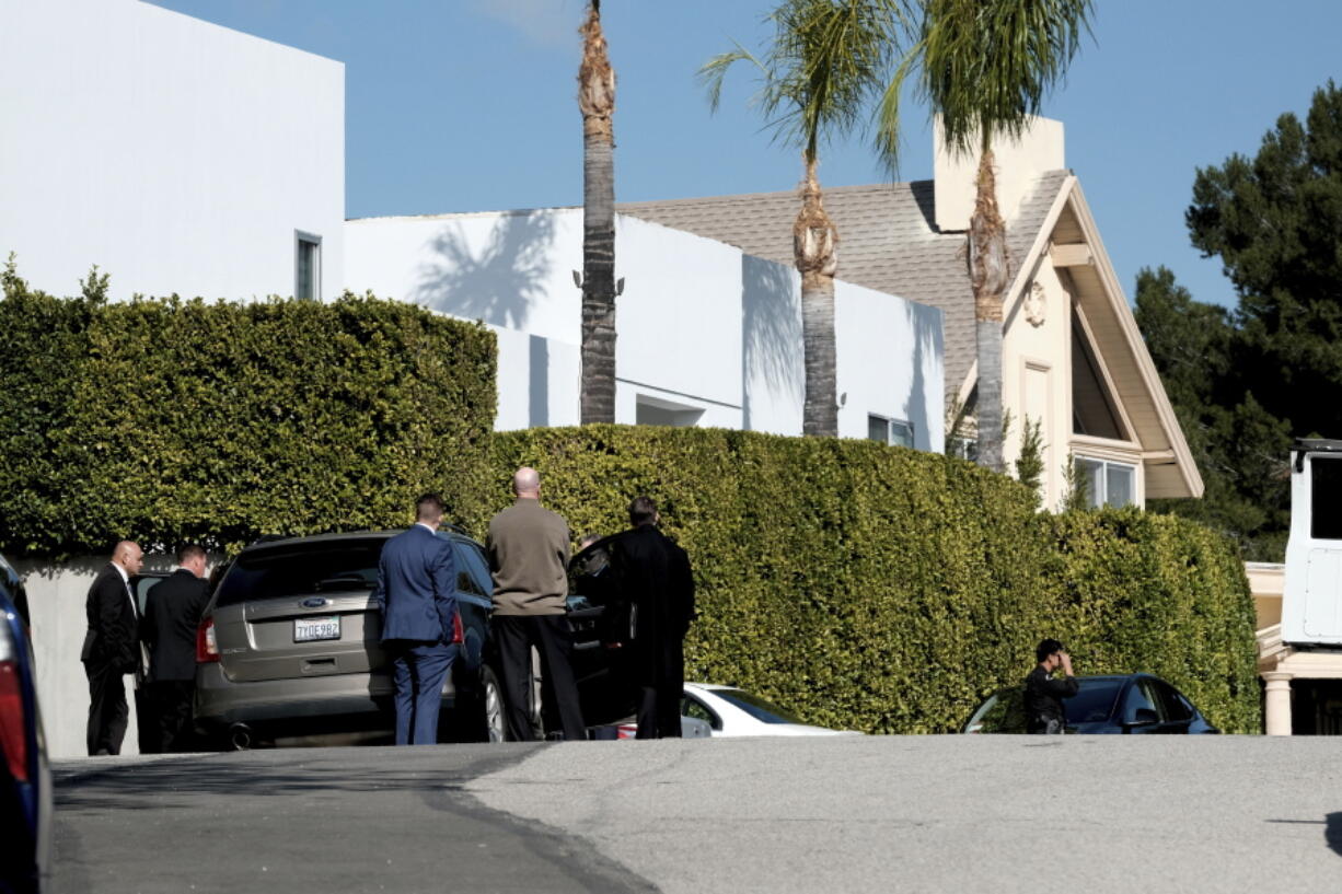 Police investigators stand in a street near a house where three people were killed and four others wounded in a shooing at a short-term rental home in an upscale Los Angeles neighborhood on Saturday Jan. 28, 2023.