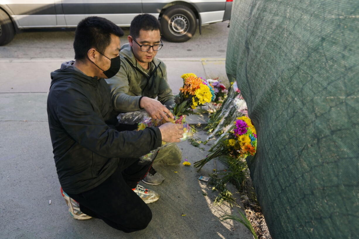 Two men place flowers near Star Dance Studio to honor victims killed in a shooting in Monterey Park, Calif., Sunday, Jan. 22, 2023. A gunman killed multiple people at a ballroom dance studio late Saturday amid Lunar New Years celebrations in the predominantly Asian American community of Monterey Park. (AP Photo/Jae C.