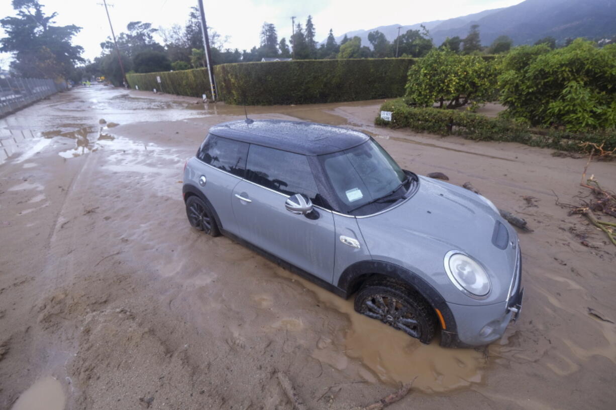 A vehicle is trapped by mud and debris at Jameson Lane near Highway 101 in Montecito, Calif., Tuesday, Jan. 10, 2023. California saw little relief from drenching rains Tuesday as the latest in a relentless string of storms swamped roads, turned rivers into gushing flood zones and forced thousands of people to flee from towns with histories of deadly mudslides.   (AP Photo/Ringo H.W.