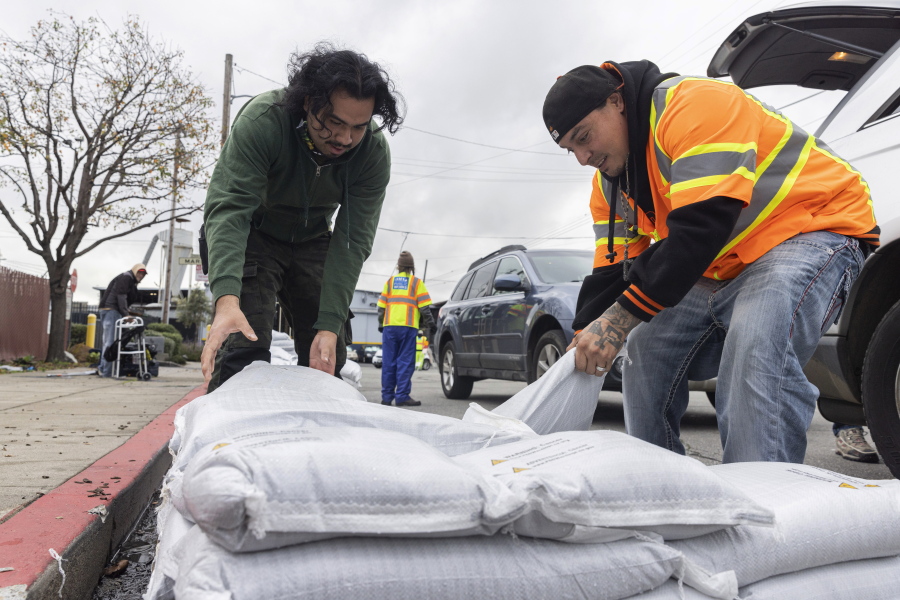 Fernando Bizarro, left, collects sandbags from an emergency distribution center to prepare for an upcoming storm, Tuesday, Jan. 3, 2023, in San Francisco.