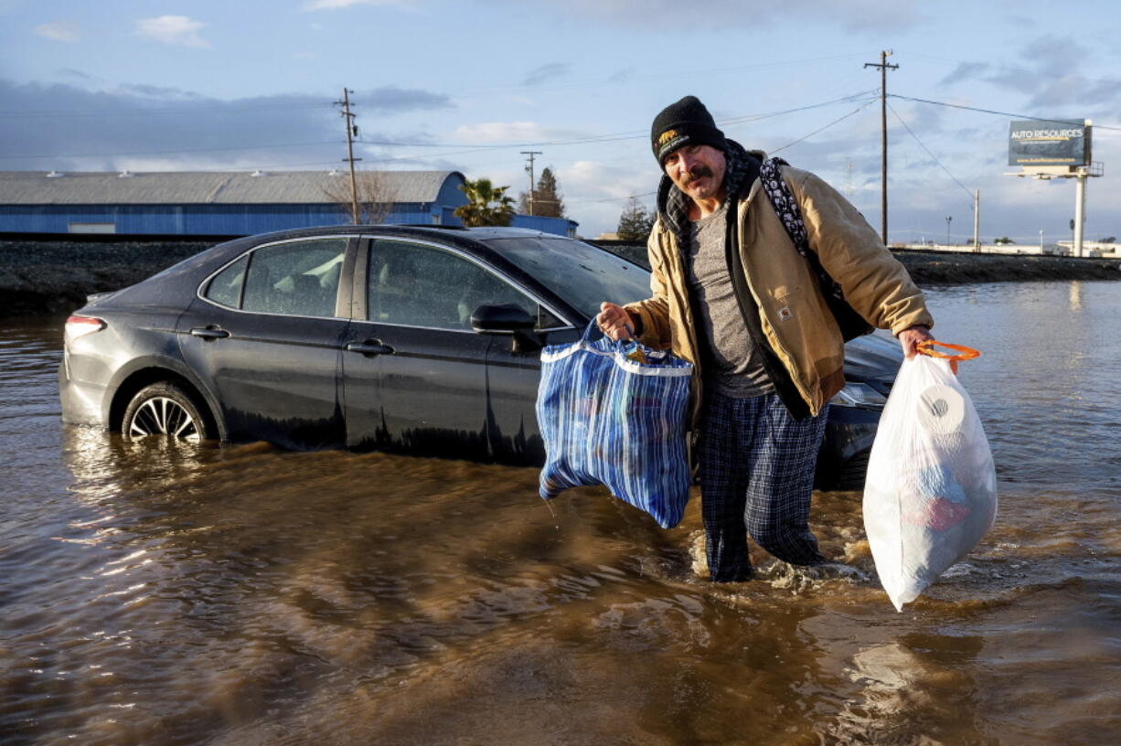 Jesus Torres carries belongings from his flooded Merced, Calif., home on Tuesday, Jan. 10, 2023.