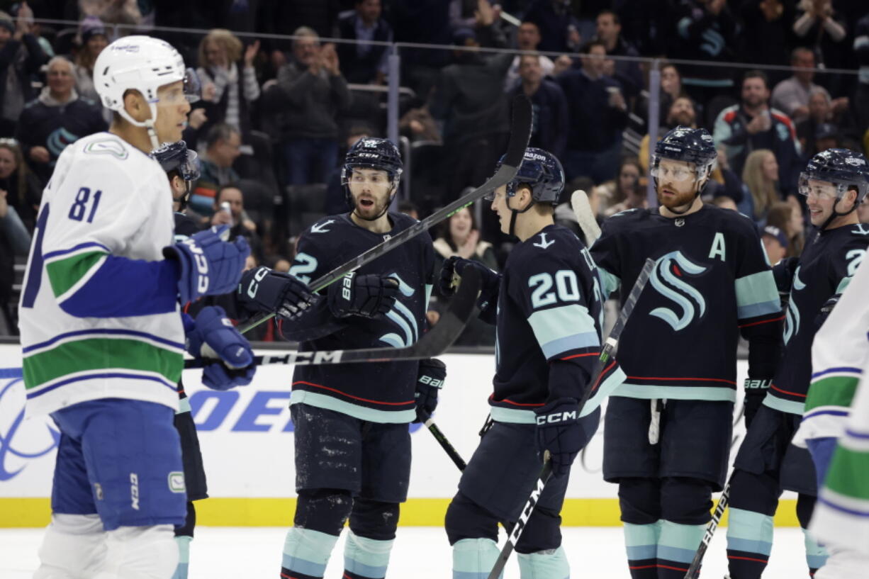 Seattle Kraken right wing Oliver Bjorkstrand (22) is congratulated by right wing Eeli Tolvanen (20) and defenseman Adam Larsson, second from right, after scoring against the Vancouver Canucks during the first period of an NHL hockey game, Wednesday, Jan. 25, 2023, in Seattle.
