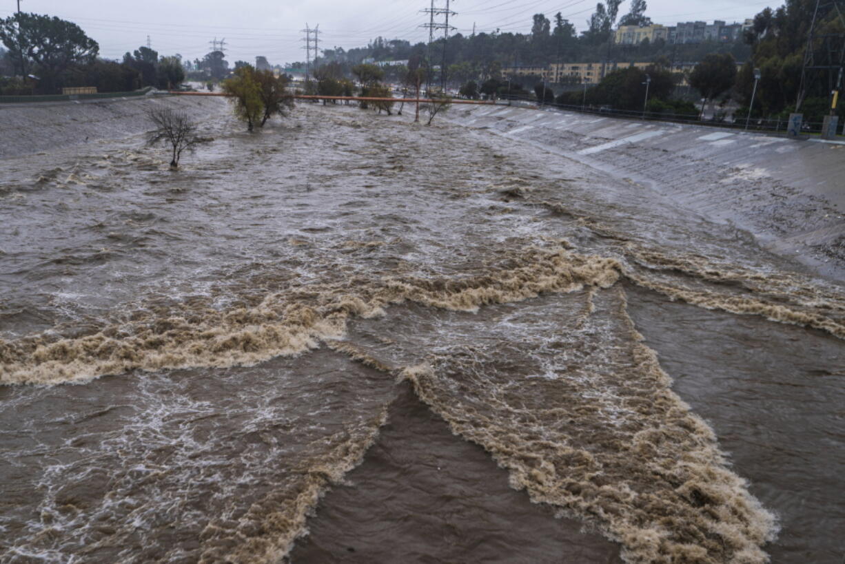 FILE - The Los Angeles River flows downstream in Los Angeles, Jan. 14, 2023. In Los Angeles, a complex system of dams and paved flood control channels including the river were designed to steer water away from roads and buildings and out to sea as fast as possible. But with water sources becoming scarce, efforts are underway to begin capturing and treating some of the runoff for irrigation or to inject in aquifers.