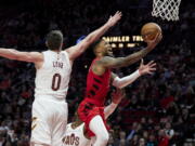 Portland Trail Blazers guard Damian Lillard, right, shoots next to Cleveland Cavaliers forward Kevin Love during the second half of an NBA basketball game in Portland, Ore., Thursday, Jan. 12, 2023.