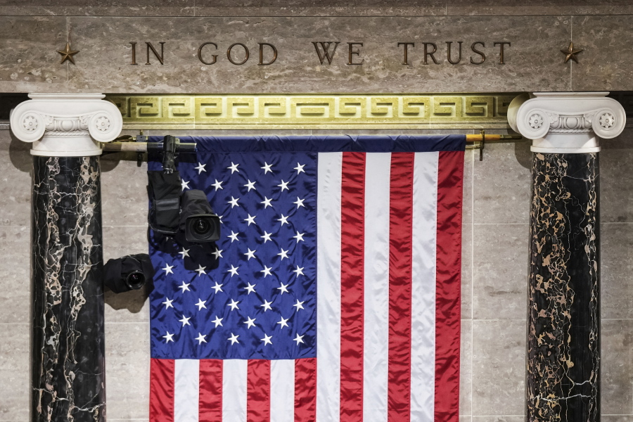 FILE - "In God We Trust" is engraved in stone above a U.S. flag in the House of Representatives chamber at the Capitol in Washington on Tuesday, March 1, 2022. Even though nearly three in 10 Americans claim no religious affiliation -- a rate that has steadily risen in recent years -- only two of the 534 incoming members of Congress will admit to as much.