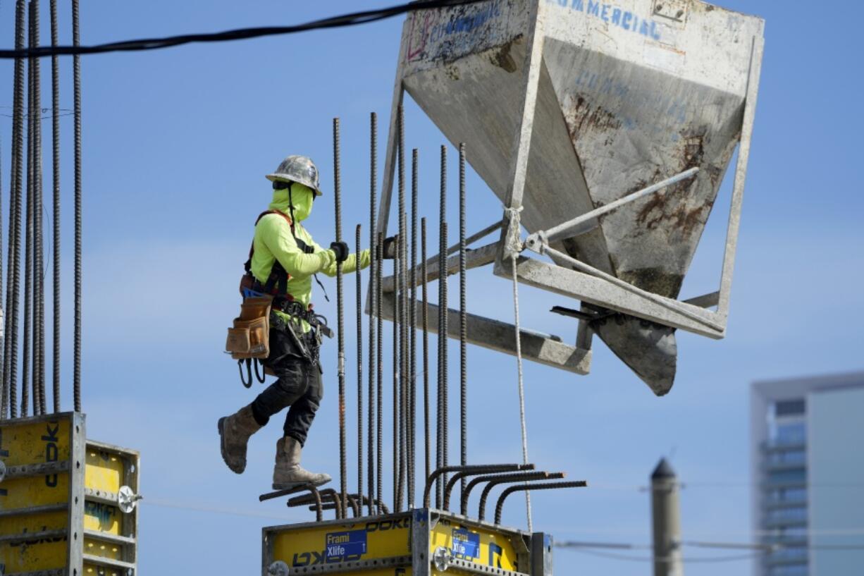 A worker guides a bin into position at a construction site, Tuesday, Jan. 24, 2023, in Miami. The Commerce Department issues its first of three estimates of how the U.S. economy performed in the fourth quarter of 2022. On Thursday, the Commerce Department issues its first of three estimates of how the U.S.