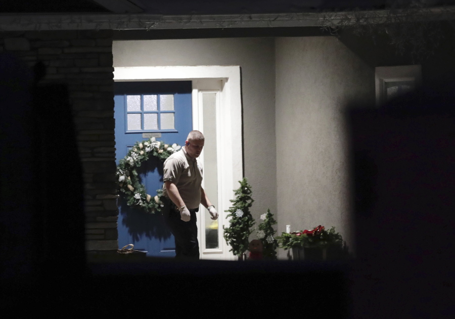 A law enforcement official stands near the front door of the Enoch, Utah, home where eight family members were found dead from gunshot wounds, Wednesday, Jan. 4, 2023. (Ben B.