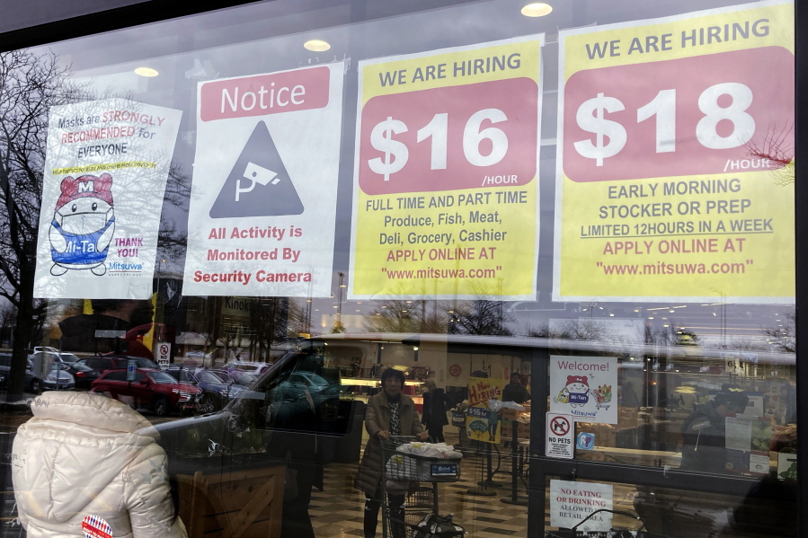 FILE - Hiring signs are displayed at a grocery store in Arlington Heights, Ill., Friday, Jan. 13, 2023. On Tuesday, the Labor Department reports on wages and benefits for U.S. workers during the October-December quarter. (AP Photo/Nam Y.