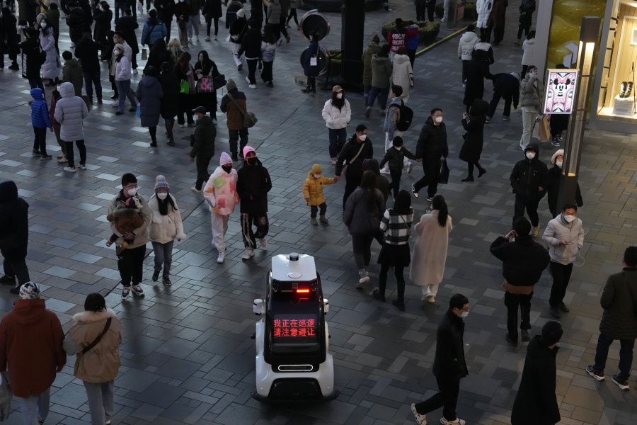FILE - A police robot vehicle patrols near the crowd that has returned to a mall following the easing of pandemic restrictions in Beijing, Sunday, Jan. 1, 2023. European Union nations are fine-tuning a coordinated response to China's COVID-19 crisis on Wednesday, Jan. 4, 2023 and are zeroing in on travel restrictions that would upset both Beijing and the global airline industry.