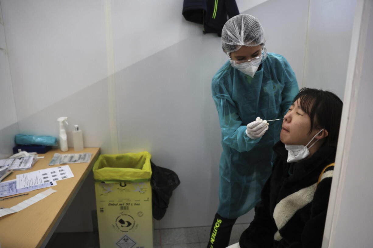 A passenger arriving from China is tested for COVID-19 at the Roissy Charles de Gaulle airport, north of Paris, Sunday, Jan. 1, 2023. France says it will require negative COVID-19 tests of all passengers arriving from China and is urging French citizens to avoid nonessential travel to China.
