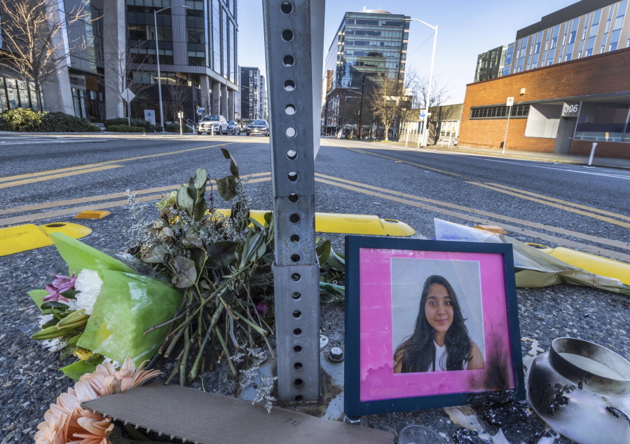 A photo of Jaahnavi Kandula is seen with flowers Sunday in Seattle at the intersection where she was killed by a Seattle Police officer driving north while responding to a nearby medical incident. Nearby, a rally saw about 50 gather to protest police violence.