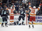 Calgary Flames defenseman MacKenzie Weegar (52) and center Elias Lindholm (28) celebrate a goal by right wing Tyler Toffoli against the Seattle Kraken during the first period of an NHL hockey game, Friday, Jan. 27, 2023, in Seattle.