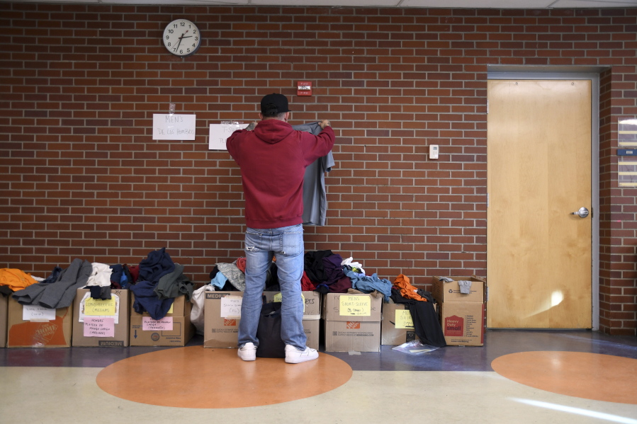 A migrant looks through donated clothes at a makeshift shelter in Denver, Friday, Jan. 6, 2023. Over the past month, nearly 4,000 immigrants, almost all Venezuelans, have arrived unannounced in the frigid city, with nowhere to stay and sometimes wearing T-shirts and flip-flops. In response, Denver converted three recreation centers into emergency shelters for migrants and paid for families with children to stay at hotels, allocating $3 million to deal with the influx.