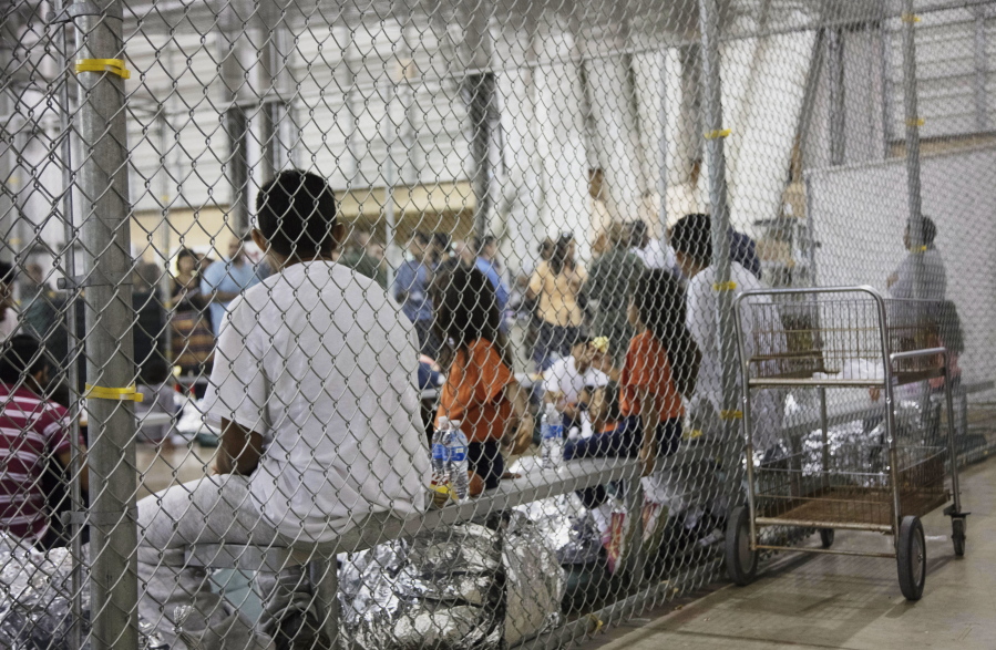 FILE - In this photo provided by U.S. Customs and Border Protection, people who've been taken into custody related to cases of illegal entry into the United States, sit in one of the cages at a facility in McAllen, Texas, on June 17, 2018. As thousands of children were taken from their parents at the southern border amid a crackdown on illegal crossings by the Trump administration, a federal public defender in San Diego set out to find new strategies to go after the longstanding deportation law fueling the family separations. (U.S.