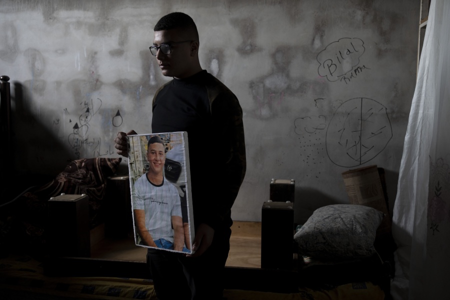 Yousef Mesheh, 15, holds a portrait of his brother, Wael in the bedroom where they were sleeping when Israeli forces stormed into their home at 3.a.m., in the Balata Refugee Camp in the northern West Bank, Tuesday, Jan. 10, 2023. They were both arrested, but Wael is still imprisoned.