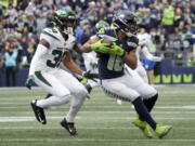 Seattle Seahawks wide receiver Tyler Lockett (16) runs after the catch as New York Jets cornerback Michael Carter II (30) defends during the first half of an NFL football game, Sunday, Jan. 1, 2023, in Seattle. (AP Photo/Ted S.