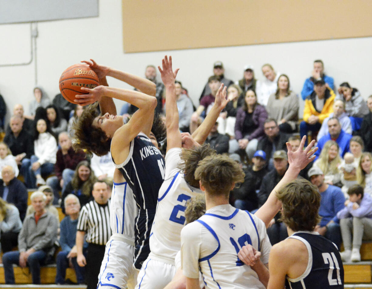 Giovanny Evanson of King’s Way Christian (in blue) has a shot blocked as drives the lane during a Trico League boys basketball game at La Center High School on Friday, Jan. 27, 2023.