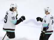 Seattle Kraken's Jared McCann (19) celebrates his hat trick with Justin Schultz during the third period of the team's NHL hockey game against the Chicago Blackhawks on Saturday, Jan. 14, 2023, in Chicago.