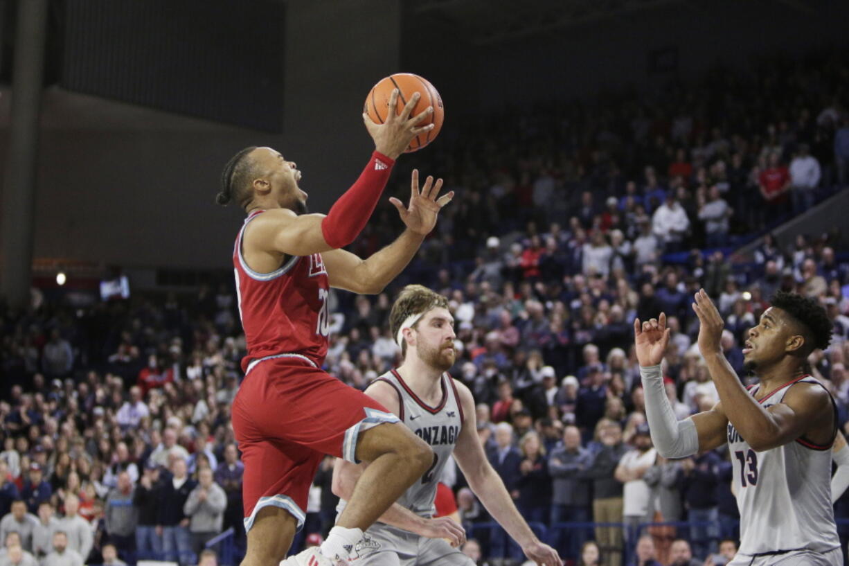 Loyola Marymount guard Cam Shelton, left, shoots the go-ahead basket in front of Gonzaga guard Malachi Smith, right, and forward Drew Timme during the second half of an NCAA college basketball game, Thursday, Jan. 19, 2023, in Spokane, Wash. Loyola Marymount won 68-67.