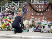 FILE - Reggie Daniels pays his respects a memorial at Robb Elementary School on June 9, 2022, in Uvalde, Texas, created to honor the victims killed in the recent school shooting. As mass shootings are again drawing public attention, states across the U.S. seem to be deepening their political divide on gun policies. A series of recent mass shootings in California come after a third straight year in which U.S. states recorded more than 600 mass shootings involving at least four deaths or injuries.