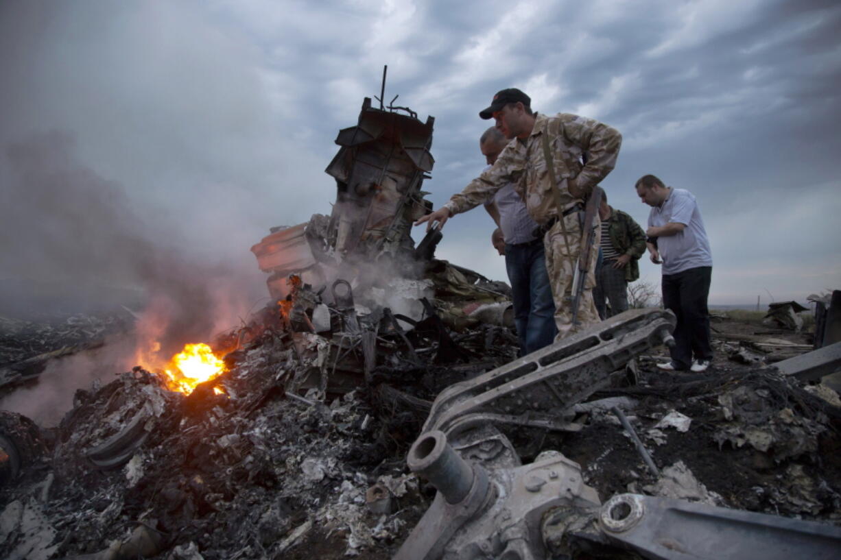 FILE - People inspect the crash site of a passenger plane near the village of Hrabove, Russian-controlled Donetsk region of Ukraine on Thursday, July 17, 2014. Europe's top human rights court ruled Wednesday, Jan. 25, 2023 that it can adjudicate on cases brought by the Netherlands and Ukraine against Russia for alleged rights violations in eastern Ukraine in 2014, including the downing of Malaysia Airlines flight MH17.