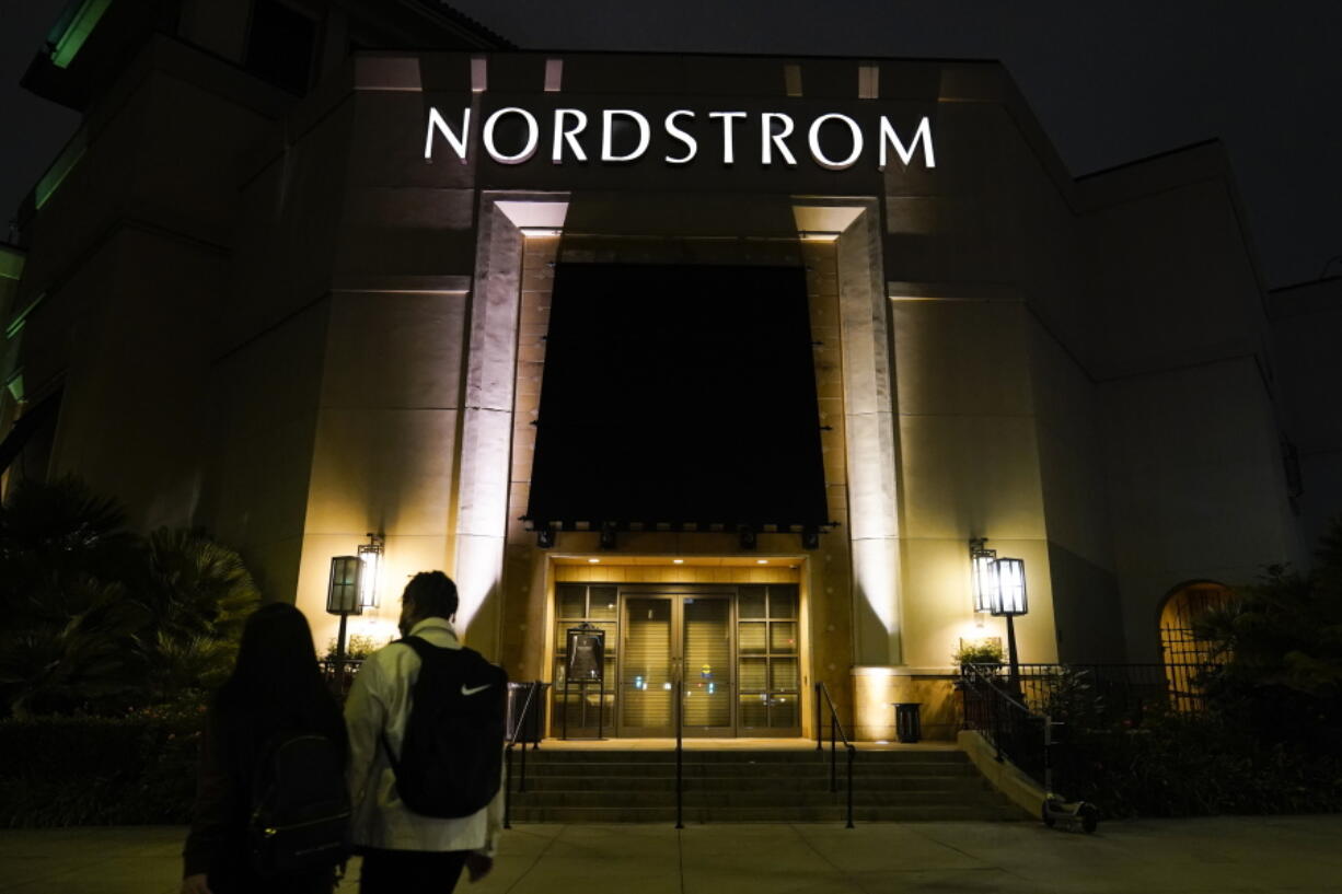 FILE - Two pedestrians walk near a closed street entrance to a Nordstrom department store at the Grove mall in Los Angeles, Thursday, Dec. 2, 2021. Shares of Nordstrom are slumping in premarket trading Friday, Jan. 20, 2023 after the upscale department store chain cut its annual profit outlook amid lackluster holiday sales that forced it to slash prices.  AP Photo/Jae C.