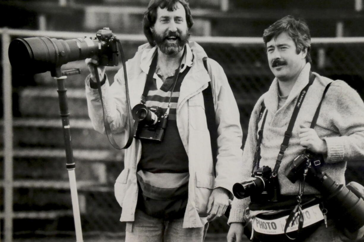 Former Associated Press photographer Jack Smith, left, is seen with fellow photographer Steven Nehl, then of the Oregonian newspaper, during an NCAA college football game in Eugene, Ore., in the early 1990s. Jack Smith, an AP photographer who captured unforgettable shots of the eruption of Mount St. Helens, the Exxon-Valdez oil spill, the Olympics and many other events during his 35-year career with the news organization, passed away on Jan. 4, 2023, at his home in La Mesa, Calif. He was 80.