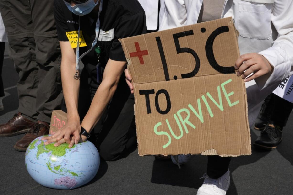 FILE - Demonstrators pretend to resuscitate the Earth while advocating for the 1.5 degree warming goal to survive at the COP27 U.N. Climate Summit, Nov. 16, 2022, in Sharm el-Sheikh, Egypt. A new study using artificial intelligence finds that the world will likely warm a few more tenths of a degrees within the next 10 to 12 years and breach a key climate change threshold aimed at limiting the worst effects of climate change.