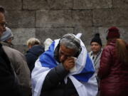 Zvika Karavany, 72, a Yemeni-born Israeli, wipes his tears in front of the Death Wall in the former Nazi German concentration and extermination camp Auschwitz during ceremonies marking the 78th anniversary of the liberation of the camp in Oswiecim, Poland, Friday, Jan. 27, 2023.