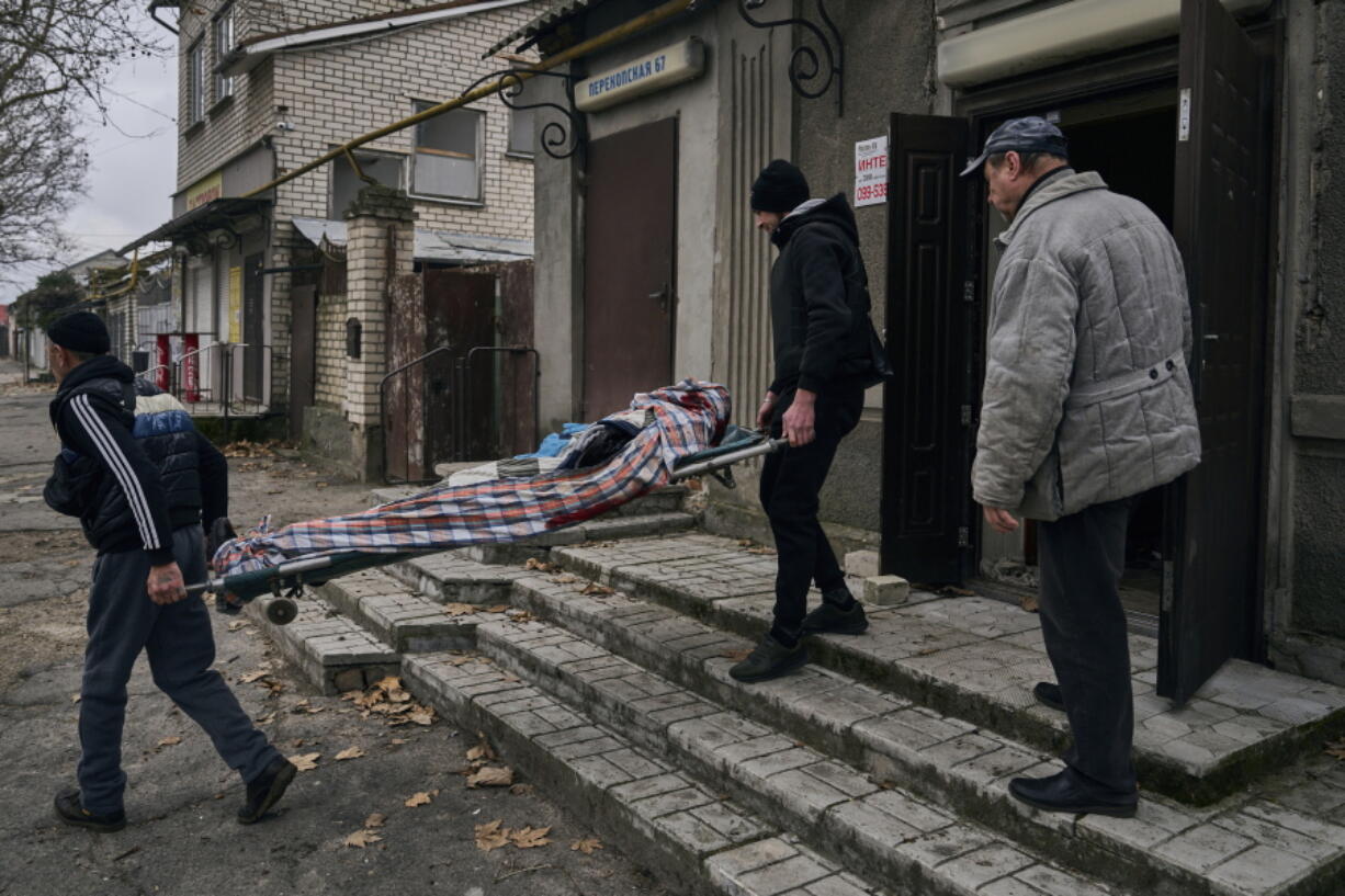 Local residents carry the body of a 20-year-old man killed in Russian shelling in Kherson, Ukraine, Thursday, Jan. 5, 2023.