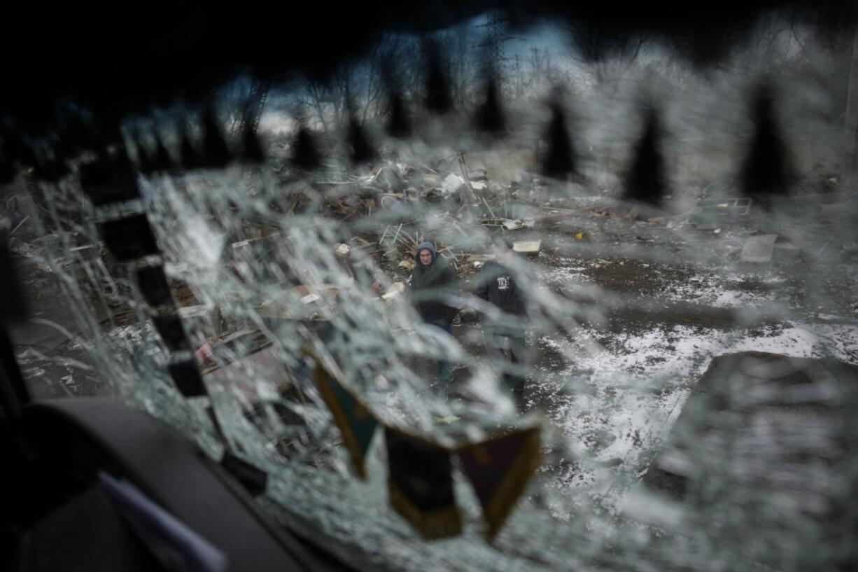Men are seen through a smashed window of a damaged truck following a rocket attack in Kyiv, Ukraine, Thursday, Jan. 26, 2023.