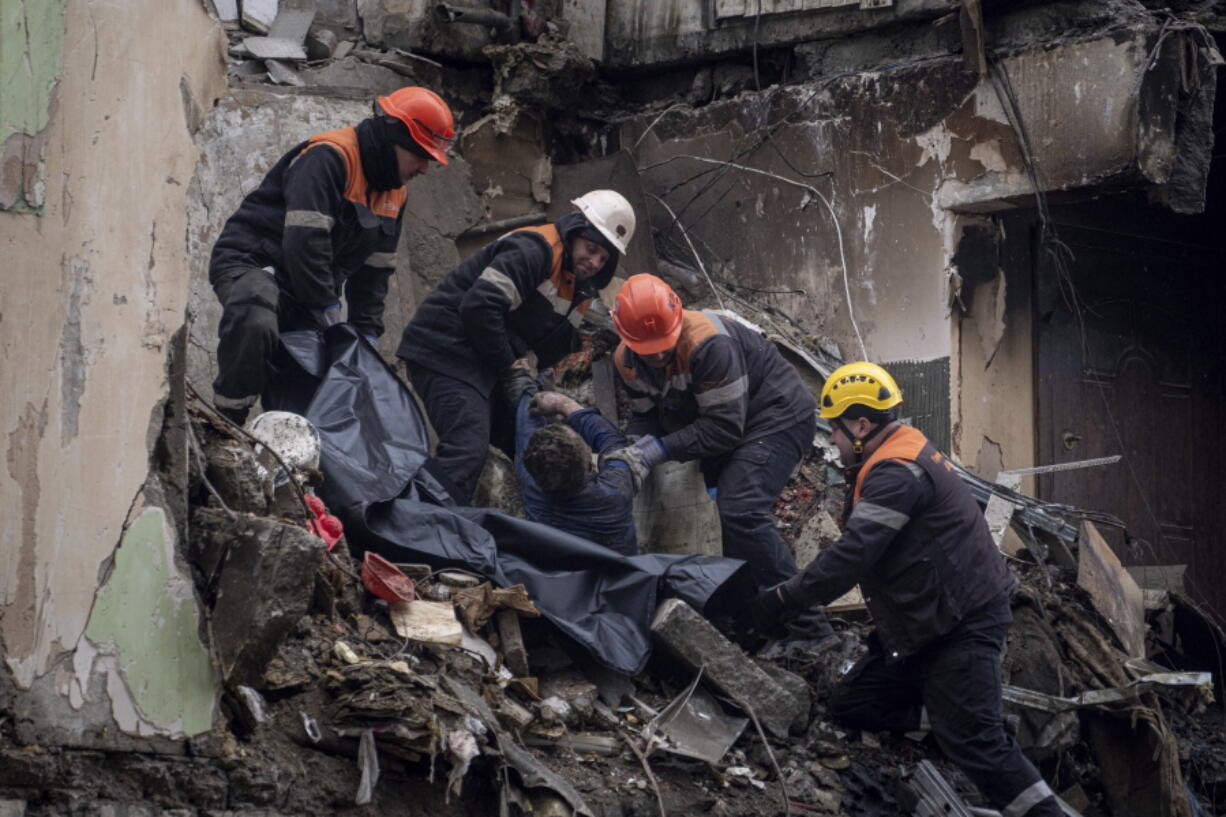 Rescue workers transfer the body of a man killed in a Russian missile strike on an apartment building, into a plastic bag in the southeastern city of Dnipro, Ukraine, Monday, Jan. 16, 2023.