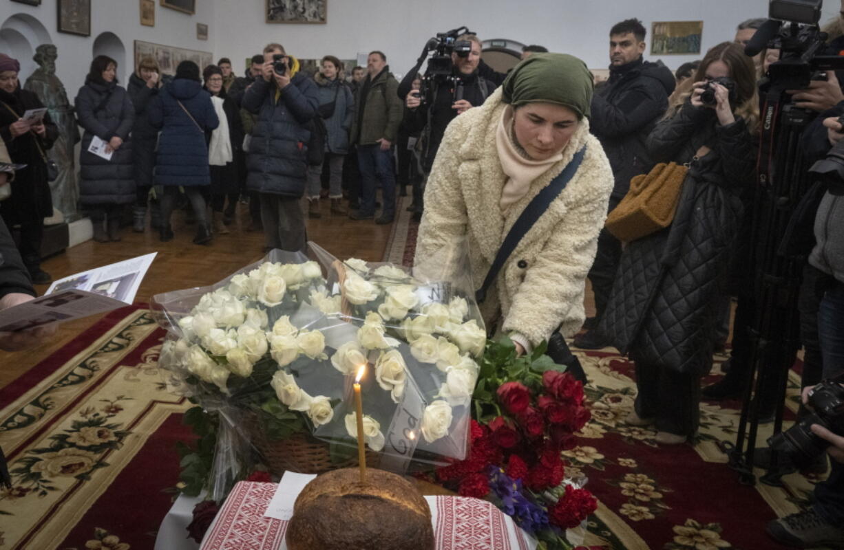 People lay flowers to commemorate British volunteers Chris Parry and Andrew Bagshaw, killed in Ukraine's war-hit east, during commemorating service in a refectory near St. Sophia Cathedral in Kyiv, Ukraine, Sunday, Jan. 29, 2023. Andrew Bagshaw was a dual New Zealand and British citizen who was killed along with British colleague Chris Parry while attempting to rescue an elderly woman from the town of Soledar when their car was hit by an artillery shell.
