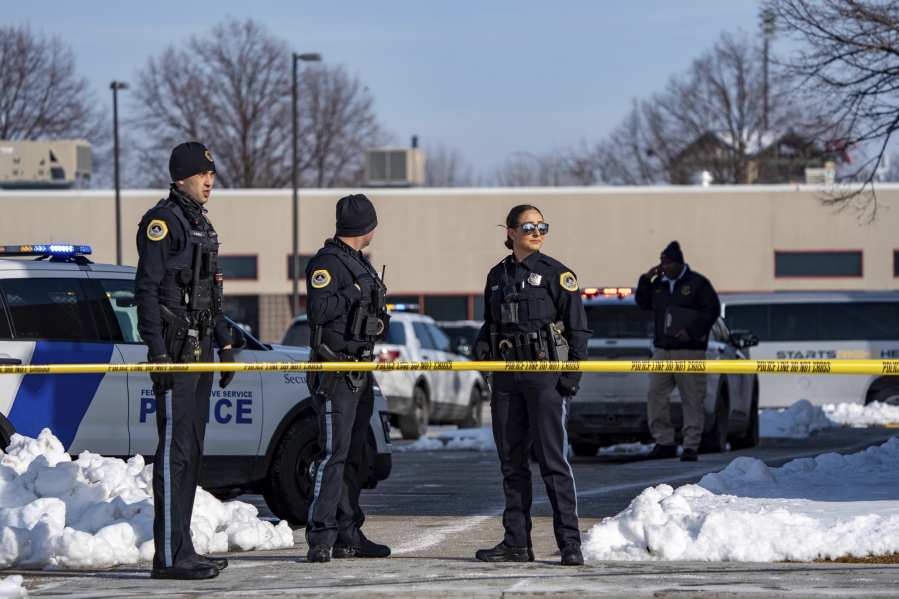 Law enforcement officers stand outside a school housing an educational program called Starts Right Here that is affiliated with the Des Moines school district, following a shooting Monday, Jan. 23, 2023, in Des Moines, Iowa.  Police say two students were killed, and an adult employee was seriously injured in the shooting at the school dedicated to helping at-risk youth.