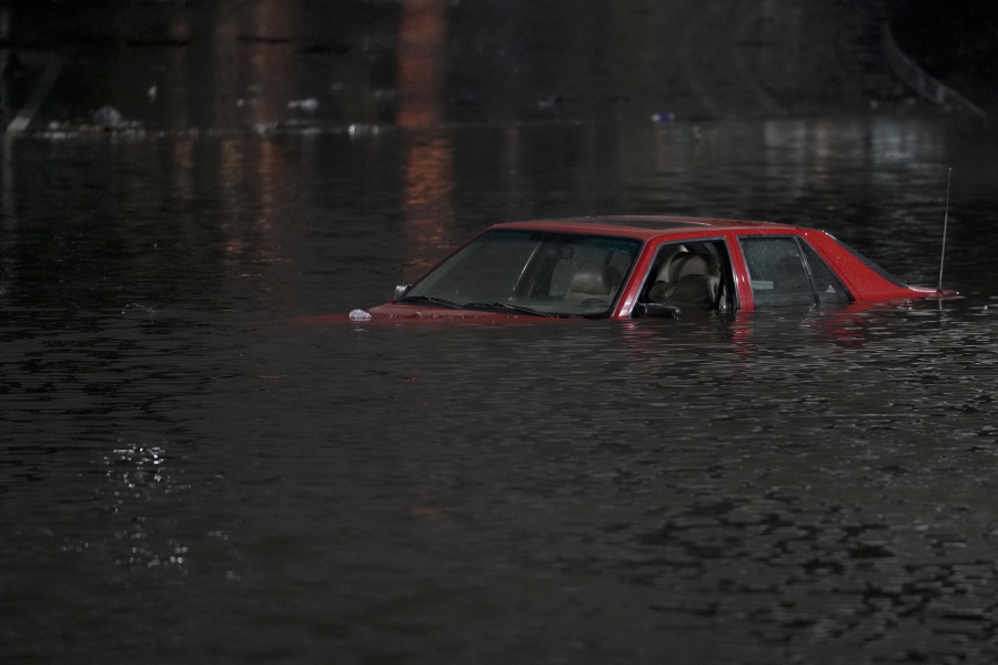 An empty vehicle is surrounded by floodwaters on a road in Oakland, Calif., Wednesday, Jan. 4, 2023. Another winter storm moved into California on Wednesday, walloping the northern part of the state with more rain and snow. It's the second major storm of the week in the parched state. (AP Photo/Godofredo A.