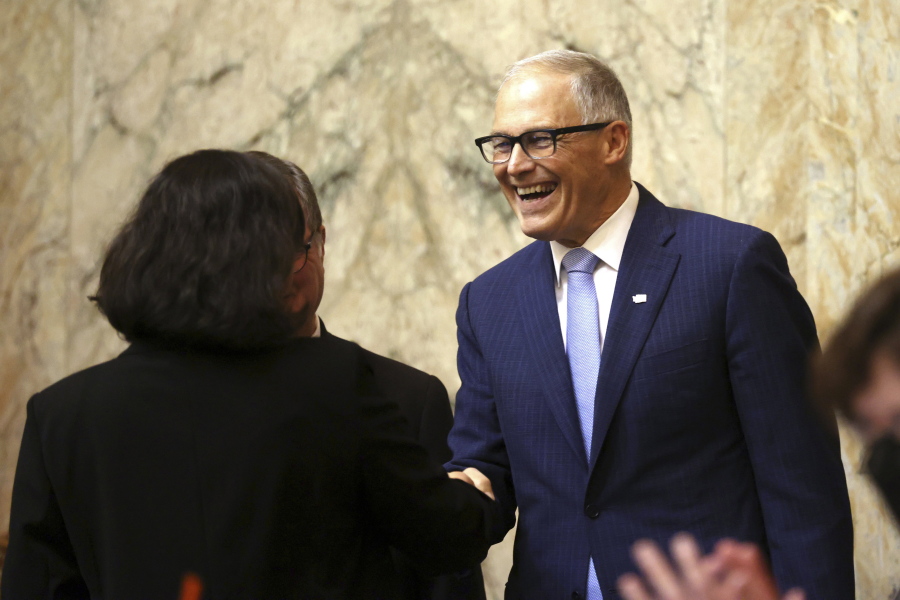 Washington Gov. Jay Inslee shakes hands with Washington state Poet Laureate Rena Priest during his 2023 State of the State address at the Capitol in Olympia, Wash., on Tuesday, Jan. 10, 2023.