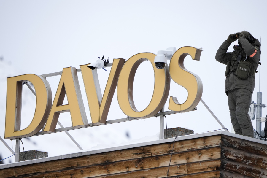 A police officer stands on the roof of a hotel and monitore the are with a binocular in Davos, Switzerland Monday, Jan. 16, 2023. The annual meeting of the World Economic Forum is taking place in Davos from Jan. 16 until Jan. 20, 2023.