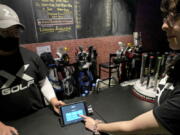 X-Golf manager J.W. Park, left, helps Ashley Moreno to check out at X-Golf indoor golf in Glenview, Ill., Friday, Jan. 20, 2023. Tipping fatigue, it seems, is swarming America as more businesses adopt digital payment methods that automatically prompts customers to leave a gratuity. (AP Photo/Nam Y.