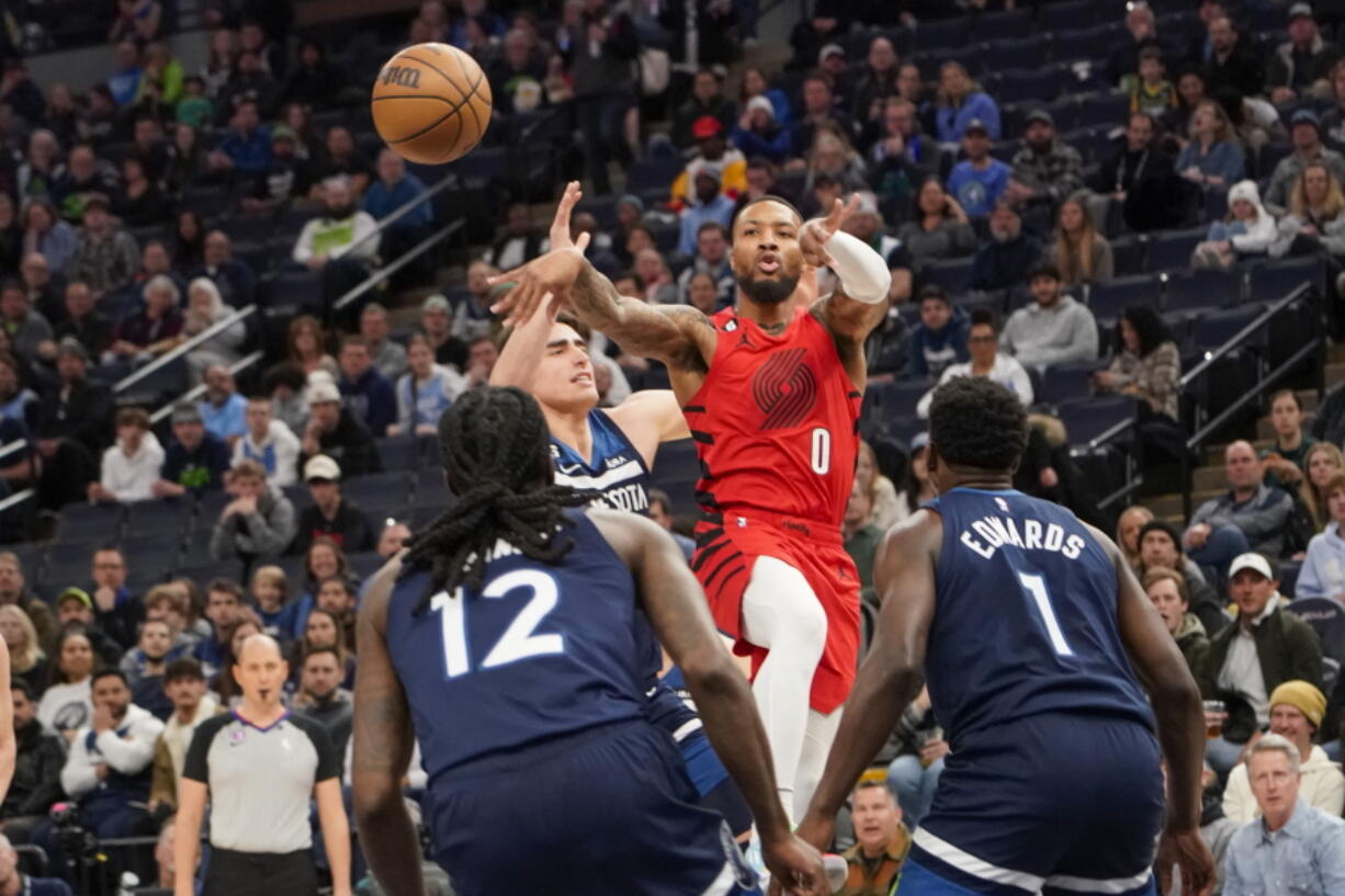 Portland Trail Blazers guard Damian Lillard (0) makes a pass over Minnesota Timberwolves center Luka Garza, second from left, forward Taurean Prince (12) and guard Anthony Edwards (1) during the first half of an NBA basketball game, Wednesday, Jan. 4, 2023, in Minneapolis.