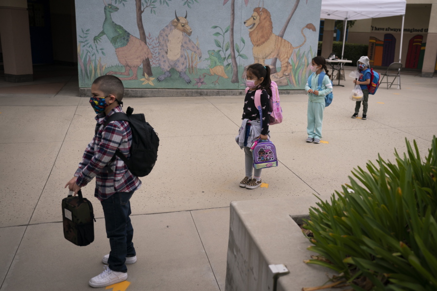Socially distanced kindergarten students wait for their parents to pick them up on the first day of in-person learning at Maurice Sendak Elementary School on April 13, 2021, in Los Angeles.