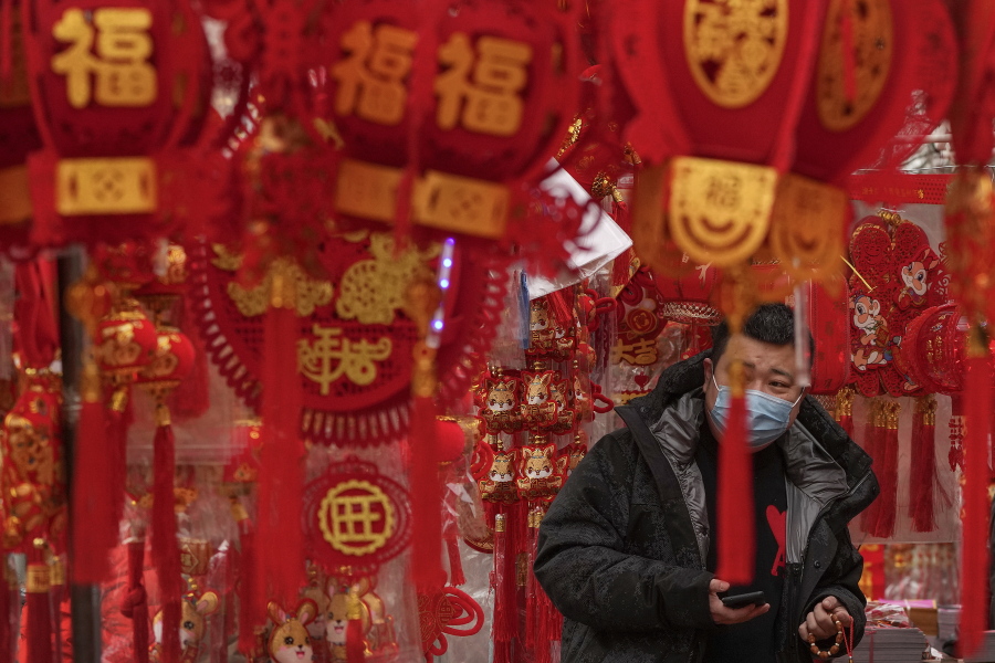A man wearing a face mask shops Saturday for Chinese Lunar New Year decorations at a store in Beijing. China has suspended or closed the social media accounts of more than 1,000 critics of the government's policies on the COVID-19 outbreak.