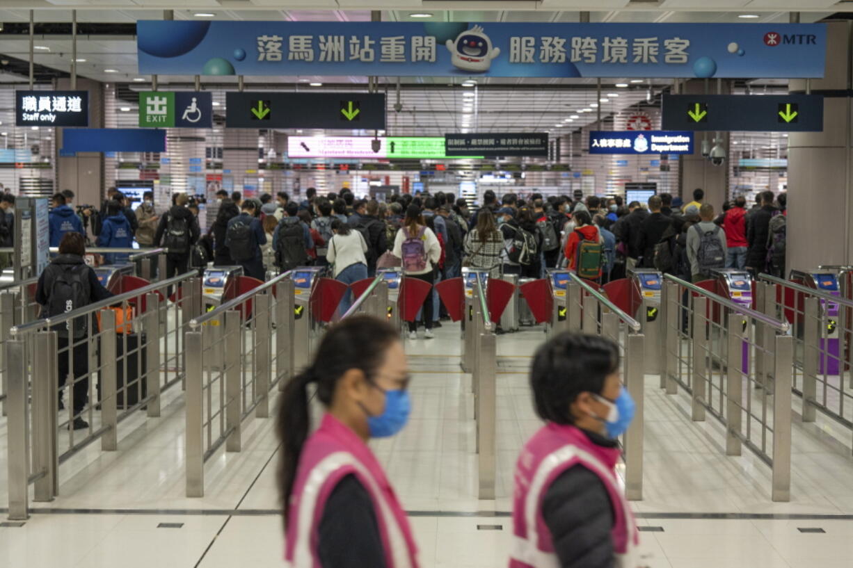 Workers wearing face masks walk by as travelers wait at the departure hall of the Lok Ma Chau station following the reopening of crossing border with mainland China, in Hong Kong, Sunday, Jan. 8, 2023. Travelers crossing between Hong Kong and mainland China, however, are still required to show a negative COVID-19 test taken within the last 48 hours, a measure China has protested when imposed by other countries.