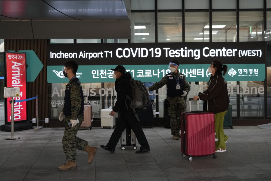 Passengers arriving from China pass by a COVID-19 testing center at the Incheon International Airport in Incheon, South Korea, Tuesday, Jan. 10, 2023. China suspended visas Tuesday for South Koreans to come to the country for tourism or business in apparent retaliation for COVID-19 testing requirements on Chinese travelers.