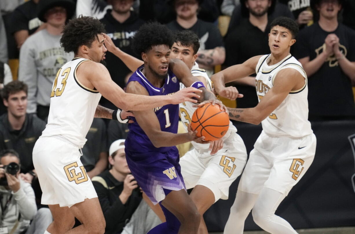 Washington forward Keion Brooks, second from left, picks up a loose ball as, from left, Colorado guard J'Vonne Hadley, forward Tristan da Silva and guard Nique Clifford defend in the second half of an NCAA college basketball game Thursday, Jan. 19, 2023, in Boulder, Colo.